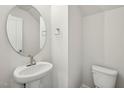 New powder room with pedestal sink, round mirror, and toilet at 919 Montague Ave, Durham, NC 27703