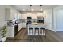 Modern kitchen featuring white cabinets, granite countertops, stainless steel appliances, and a large center island with seating at 93 Butterbean Ct, Zebulon, NC 27597