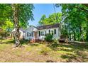 Charming single-story house with a covered porch and black shutters surrounded by mature trees at 1003 E Club Blvd, Durham, NC 27704