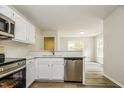 Modern kitchen with stainless steel appliances, white cabinetry, and a pass-through to the living area at 1003 Walnut Dr, Erwin, NC 28339