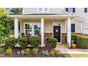 Inviting front porch with stone accents, rocking chairs and manicured landscaping for relaxation at 108 Yosemite Ct, Holly Springs, NC 27540