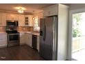 Bright kitchen featuring stainless steel appliances, white cabinetry, and wood flooring at 157 Thorpe St, Henderson, NC 27536