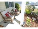 Cozy front porch with wicker chairs and decorative pillows surrounded by lush landscaping at 1940 Dunfield Dr, Fuquay Varina, NC 27526