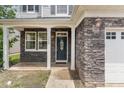 Elegant home entrance with a decorative front door, stylish lighting, and stone facade at 196 Norwich Dr, Clayton, NC 27520