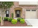 Close-up of brick front exterior with an arched front door entry and an attached garage at 2211 Sweet Annie Way, Wake Forest, NC 27587