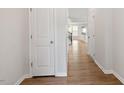 Bright hallway with wood floors, white walls, and doors leading to other areas of the home at 2211 Sweet Annie Way, Wake Forest, NC 27587