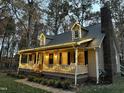 Inviting home with holiday lights, rocking chairs on the porch, and brick chimney at 2603 Red Pine Rd, Hillsborough, NC 27278