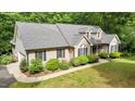 Angled view of tan home with dark shutters, grey roof, and lush green landscape at 2917 Kesler Trl, Mebane, NC 27302