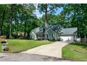 Inviting home with a spacious driveway, attached garage, and a lush green lawn surrounded by mature trees at 305 Monterey Ct, Benson, NC 27504