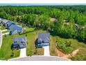 Aerial shot of a beautifully landscaped property with a gray two-story home backing to a lush wooded area at 325 Porterfield Dr, Youngsville, NC 27596
