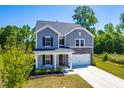 Inviting two-story home featuring gray siding, stone accents, a manicured lawn, and a welcoming front porch at 325 Porterfield Dr, Youngsville, NC 27596