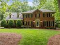 Beautiful brick home with lush green lawn, mature trees, and manicured shrubs, offering a welcoming and serene atmosphere at 4505 Wood Valley Dr, Raleigh, NC 27613