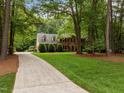 Brick home with a long driveway, lush lawn, mature trees, and neat landscaping, offering a picturesque setting at 4505 Wood Valley Dr, Raleigh, NC 27613