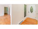 Foyer with hardwood floors, a white front door with an oval window, and an open doorway at 4832 Brookhaven Dr, Raleigh, NC 27612