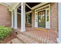 Inviting front porch showcasing brick flooring, white columns, and a welcoming front door at 5217 Roswellcrest Ct, Apex, NC 27539