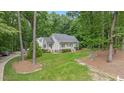 Beautiful white cottage-style home nestled among mature trees with a lush green lawn at 5241 Mill Dam Rd, Wake Forest, NC 27587