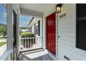 A welcoming red front door is showcased with a screened-in porch and a view of landscaped surroundings at 605 Larchwood Dr, Durham, NC 27713