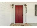 Inviting red front door with classic sconces and stone landing at 7227 Cleveland Rd Rd, Clayton, NC 27520