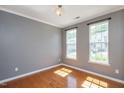 Inviting bedroom with hardwood floors, two bright windows, and neutral paint at 7616 Satinwing Ln, Raleigh, NC 27617