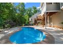 Inviting kidney shaped in-ground pool surrounded by a concrete patio and lush landscaping at 8724 Deerland Grove Dr, Raleigh, NC 27615