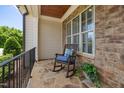 Cozy front porch with stone flooring, rocking chair, and classic railing, perfect for relaxing outdoors at 937 Sedgefield Park Ln, Cary, NC 27519