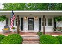 Inviting front porch featuring brick steps and an American flag, with welcoming decor at 102 Lake Dr, Wendell, NC 27591
