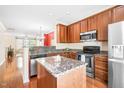 Well-lit kitchen features wood cabinets, stainless steel appliances, granite counters, and an island at 1028 Summerhouse Rd, Cary, NC 27519
