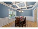 Elegant dining room featuring a coffered ceiling, hardwood floors, and ample natural light from a large window at 105 Blue Prince Trl, Holly Springs, NC 27540