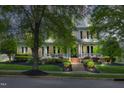 Elegant two-story home with a charming front porch, lush landscaping, and classic architectural details at 10523 Bedfordtown Dr, Raleigh, NC 27614