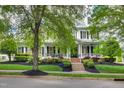 Elegant two-story home with a charming front porch, lush landscaping, and classic architectural details at 10523 Bedfordtown Dr, Raleigh, NC 27614