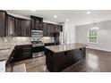 Well-equipped kitchen featuring granite countertops, stainless appliances, dark cabinets, and a spacious island at 1101 Boxcar Way, Apex, NC 27502