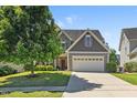 Charming home featuring a manicured lawn, two car garage, and stone and gray shingle exterior at 117 Woodlark Ln, Holly Springs, NC 27540