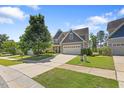 Charming home featuring a manicured lawn, two car garage, and stone and gray shingle exterior at 117 Woodlark Ln, Holly Springs, NC 27540
