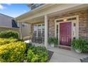 Inviting front porch with stone accents, rocking chairs, lush plants, and a vibrant maroon front door at 117 Woodlark Ln, Holly Springs, NC 27540
