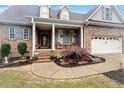 Inviting brick home showcasing a cozy covered porch with seating and a well-maintained front garden at 151 Donnibrook, Fuquay Varina, NC 27526