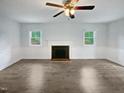 Bright living room with fireplace, ceiling fan, and natural light from the windows at 1522 Goodwin Rd, Durham, NC 27712
