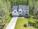 An aerial view shows a beautiful home with a long driveway surrounded by mature trees and a landscaped front yard at 1723 River Club Way, Franklinton, NC 27525