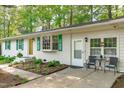 Side exterior view featuring a white brick facade, green shutters, a small patio, and landscaping at 1805 Holly St, Apex, NC 27502