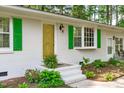 Close up of the front entrance featuring white brick, green shutters, and a golden front door at 1805 Holly St, Apex, NC 27502