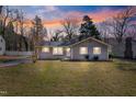 Charming single-story home featuring a landscaped yard and classic architectural details at sunset at 205 Coachman Dr, Garner, NC 27529