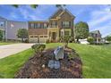 Elegant brick home with manicured front lawn, a two-car garage, and tasteful landscaping at 205 Olive Field Dr, Holly Springs, NC 27540