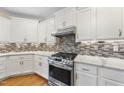 Gourmet kitchen with stainless steel range, stylish backsplash, and marble countertops at 205 Olive Field Dr, Holly Springs, NC 27540