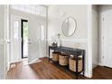 Welcoming foyer with stylish console table, round mirror, wood floors, and natural light streaming in from the doorway at 2301 Bolingbrook Ln, Raleigh, NC 27613