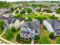 Aerial view of a blue home in a community with lush greenery, tree-lined streets, and a central park at 281 N Serenity Hill Cir, Chapel Hill, NC 27516