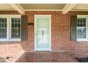 Close-up of a brick home entrance featuring a light blue door, symmetrical windows, and a decorative brick floor at 305 E Holmes St, Benson, NC 27504