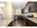Modern kitchen features stainless steel appliances, dark wood cabinets, granite countertops, and hardwood floors at 3945 Amelia Park Dr, Raleigh, NC 27606