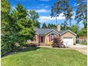 Inviting home with a green lawn, tidy landscaping, and a charming entrance with red door and shutters at 5909 Royal Coach Ct, Raleigh, NC 27612