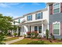 Three townhomes with manicured lawns and covered front porches, with red and green door/shutter accents at 1027 Myers Point Dr, Morrisville, NC 27560