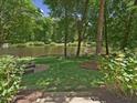 Spacious backyard featuring a fire pit, lush greenery, and serene lake views at 105 Highlands Lake Dr, Cary, NC 27518