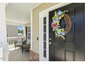 Inviting front door adorned with a colorful wreath, leading to a cozy front porch at 109 Lyngrove St, Holly Springs, NC 27540